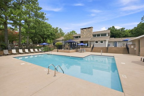 A large outdoor swimming pool with a stone building in the background.