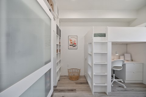a small room with a bunk bed and a desk with a chair