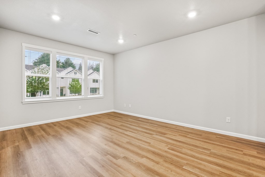 an empty living room with wood floors and a window