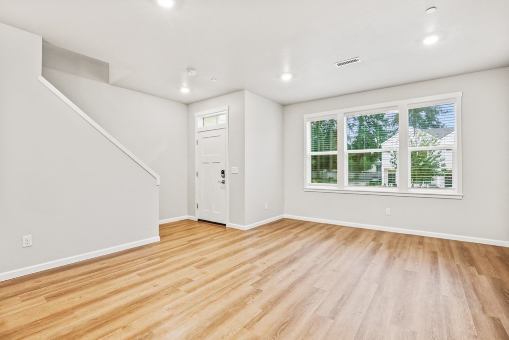 an empty living room with white walls and wood floors