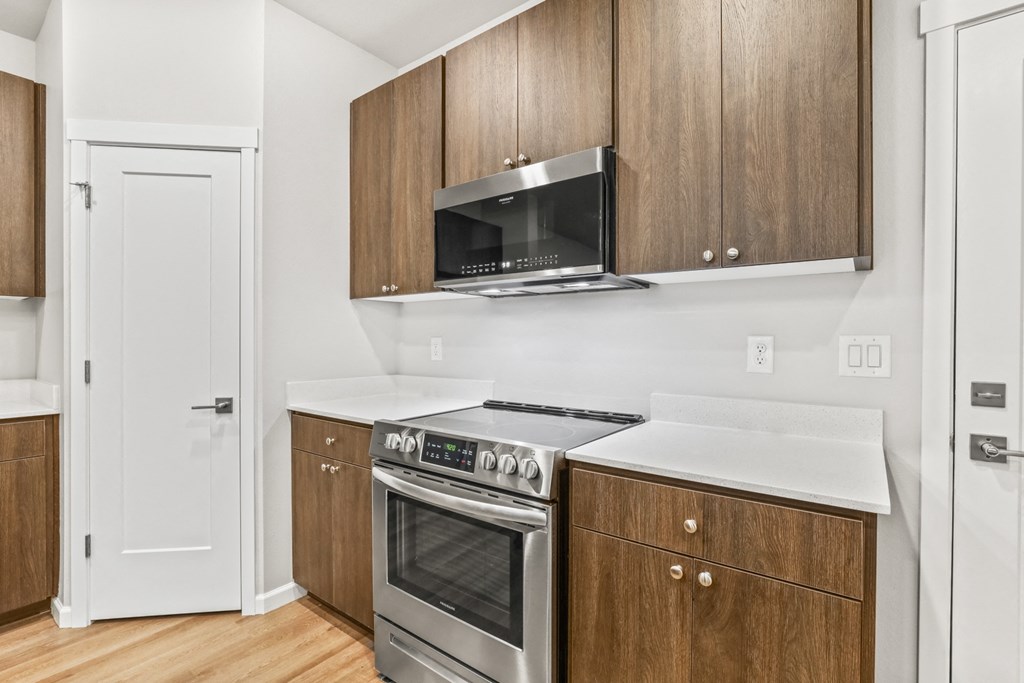 a kitchen with wooden cabinets and a stove and microwave