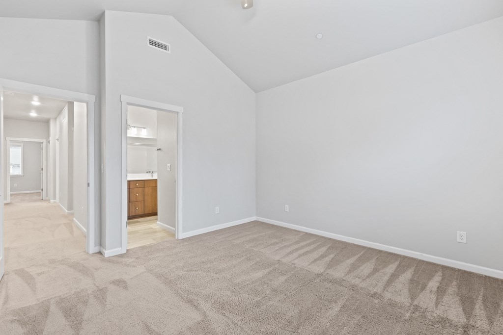 the living room and dining room of an apartment with white walls and carpet