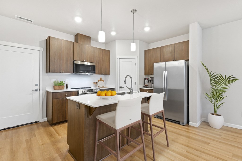 a kitchen with wooden cabinets and a white island with three stools