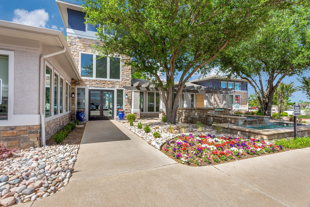 a sidewalk in front of a house with trees and flowers