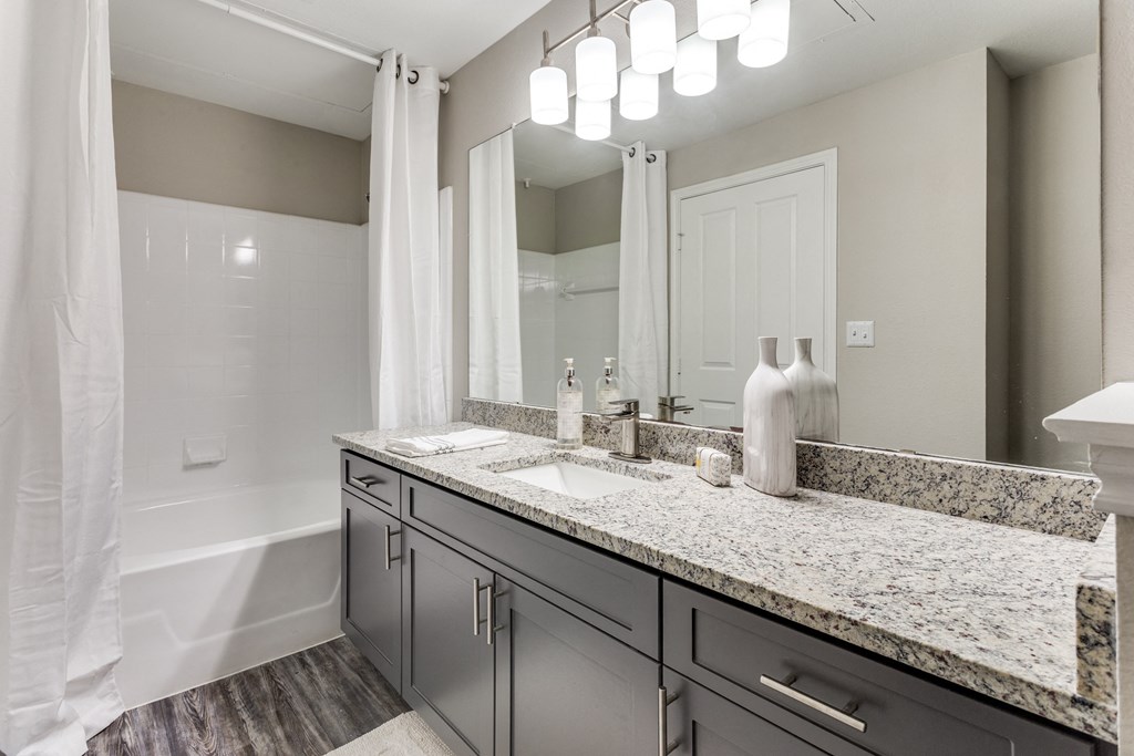a bathroom with granite counter tops and a shower and sink