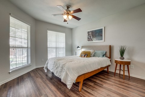 A bedroom with a bed, a ceiling fan, and a small table.