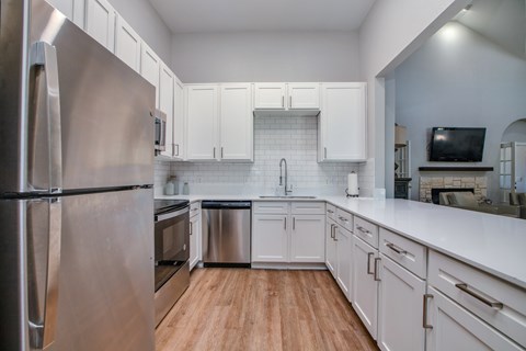 A modern kitchen with white cabinets and a stainless steel refrigerator.