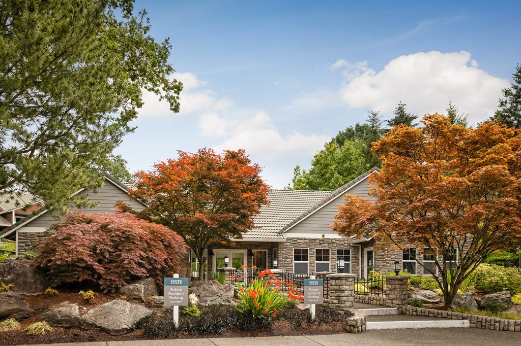the front of a gray house with trees and a garden