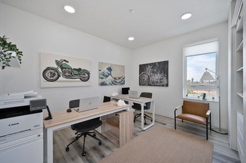 two desks with computers and a chair in a room with a window