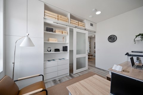 a home office with a desk and a closet with shelves