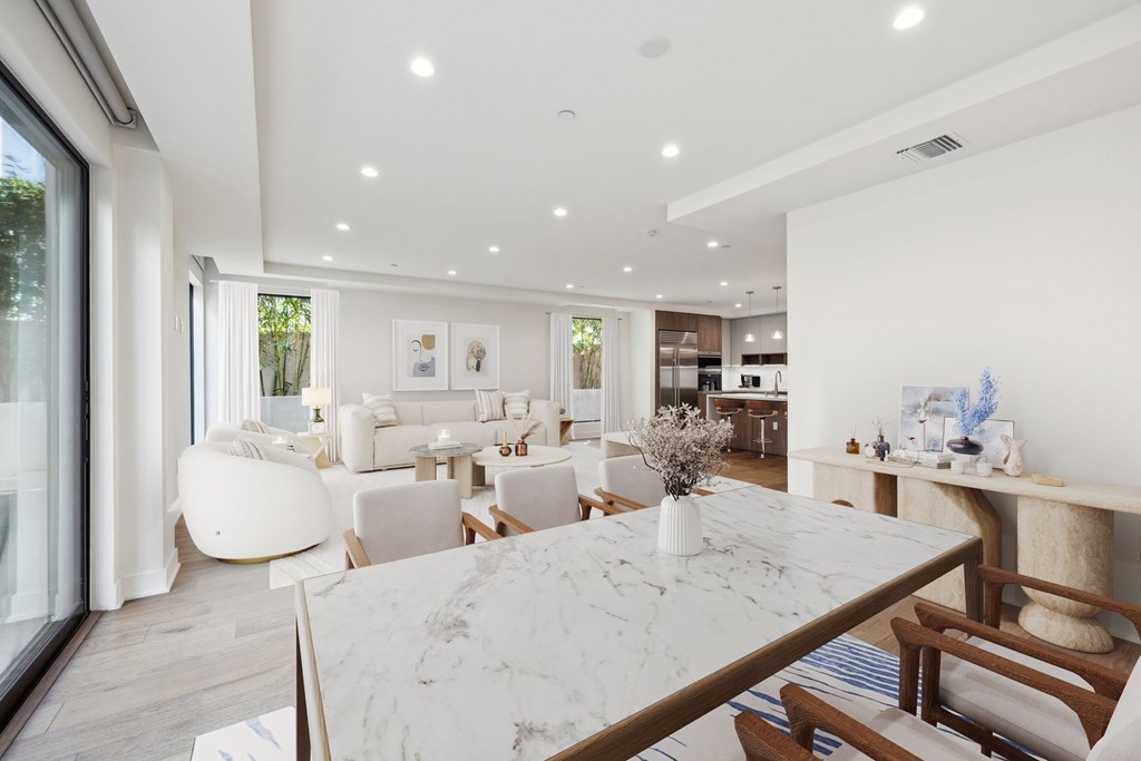 A modern dining room and living room with a marble table and white furniture.
