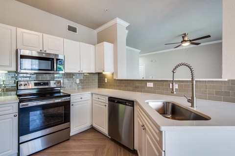 A modern kitchen with white cabinets and stainless steel appliances.