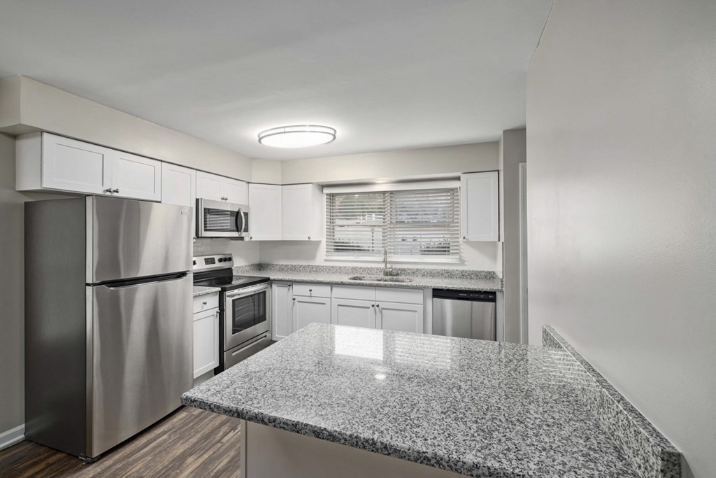 kitchen with white cabinets, granite counter tops, stainless steel appliances and large window above sink area
