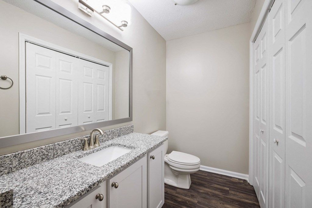 Bathroom with granite counter tops, bath tub and closet with full washer and dryer