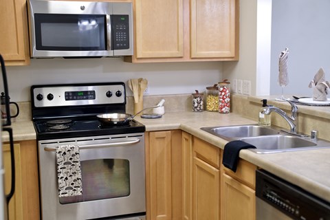 A kitchen with wooden cabinets and a stainless steel oven.