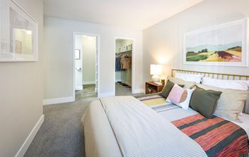 A bedroom with a large bed and a painting on the wall.