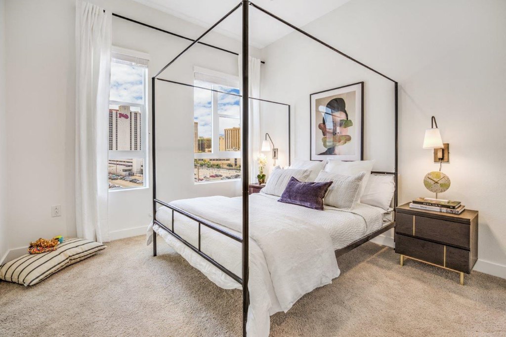 a bedroom with a large bed and two windows