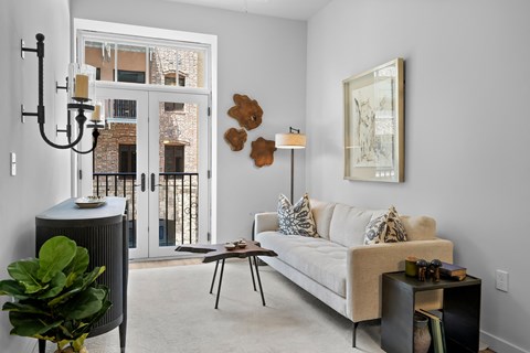 A living room with a couch, a table, a plant, and a painting on the wall.
