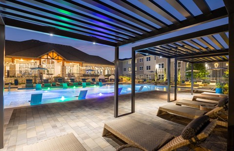 a swimming pool with lounge chairs and umbrellas at night