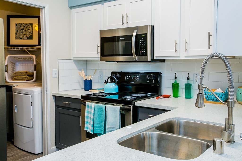 A kitchen with a stove, sink, and refrigerator.