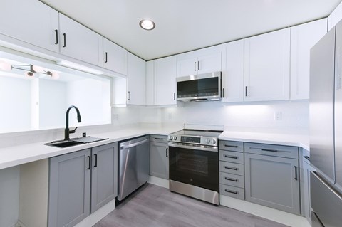 A modern kitchen with white cabinets and stainless steel appliances.