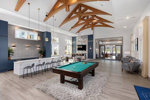 A room with a pool table and a bar area.
