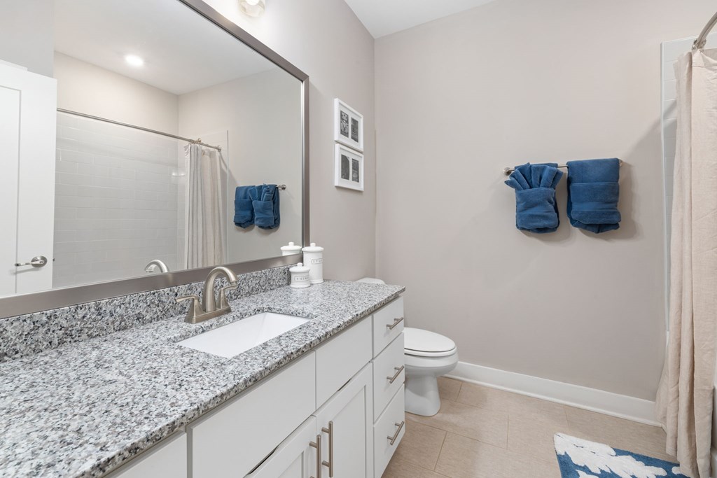 A bathroom with a marble countertop and white fixtures.