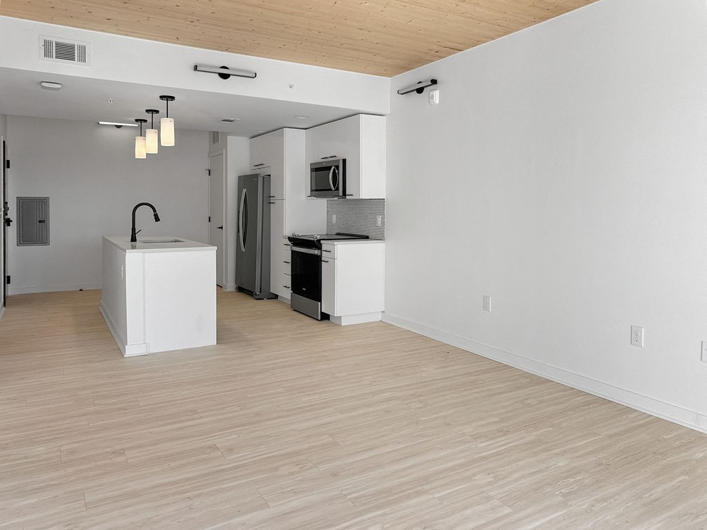 an empty kitchen and living room with a wood floor