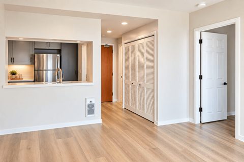 A kitchen with a refrigerator, wooden floors, and a white door.
