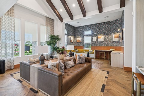 A living room with a brown leather couch and a wooden floor.