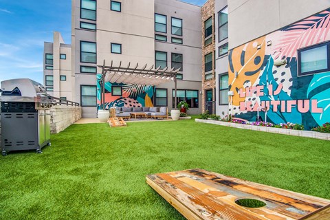A backyard with a wooden deck and a mural on the wall.