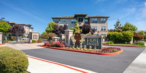 The image shows a beautiful entrance to Fiori Estates with a sign and a well-maintained garden.