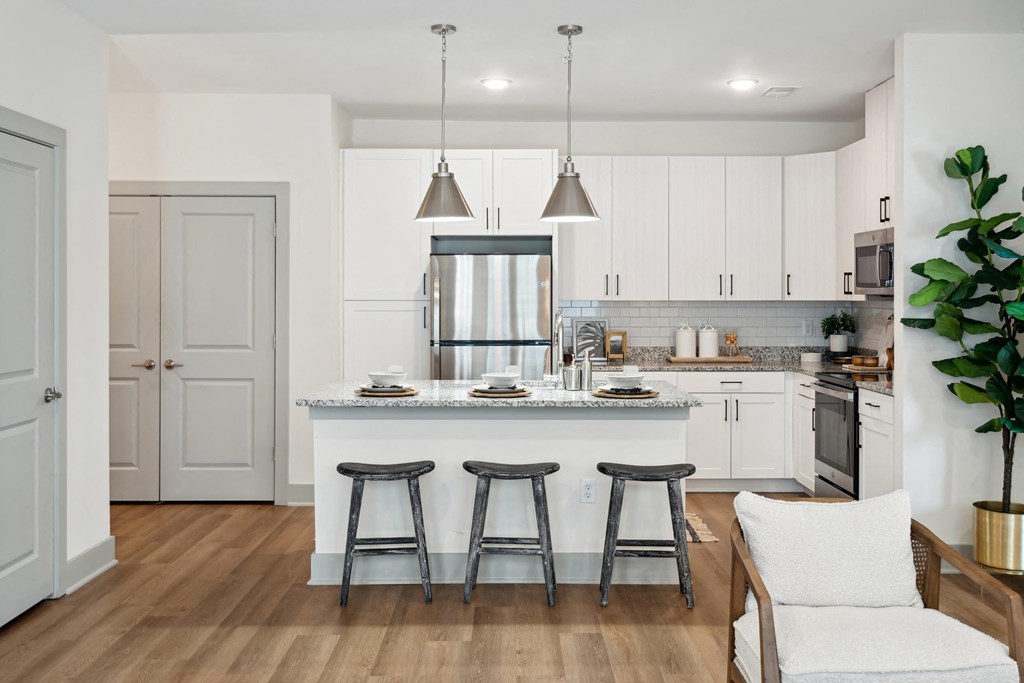a kitchen with white cabinets and a large island with three stools