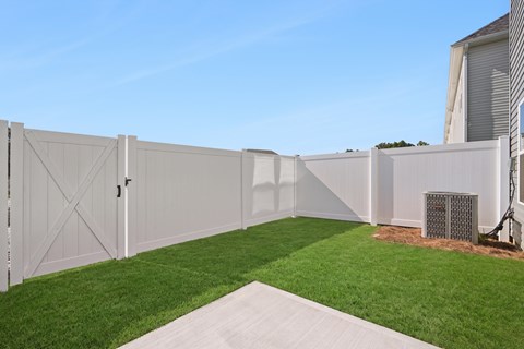 A white fence with a gate and a concrete pathway in front of it.