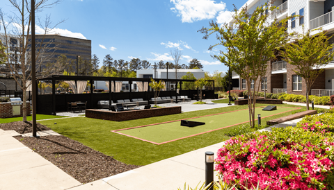 A park area with a tennis court and a building in the background.
