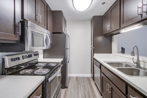 A modern kitchen with dark brown cabinets and stainless steel appliances.