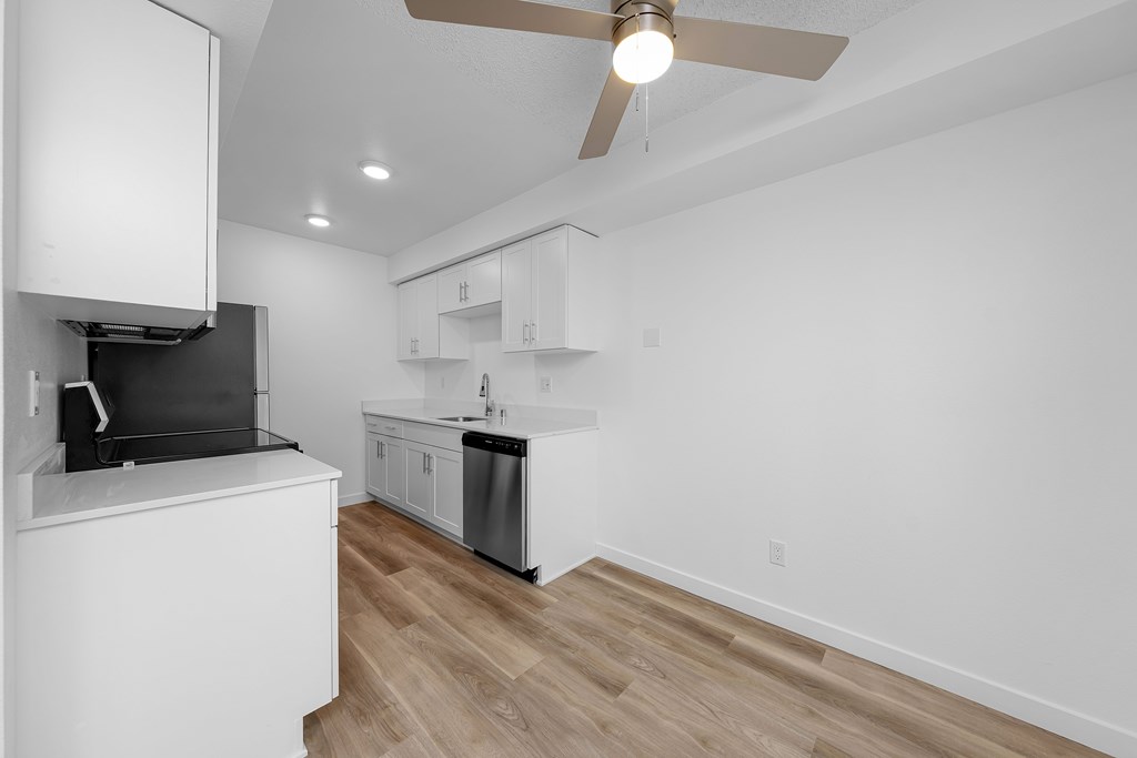 A modern kitchen with white cabinets and a wooden floor.