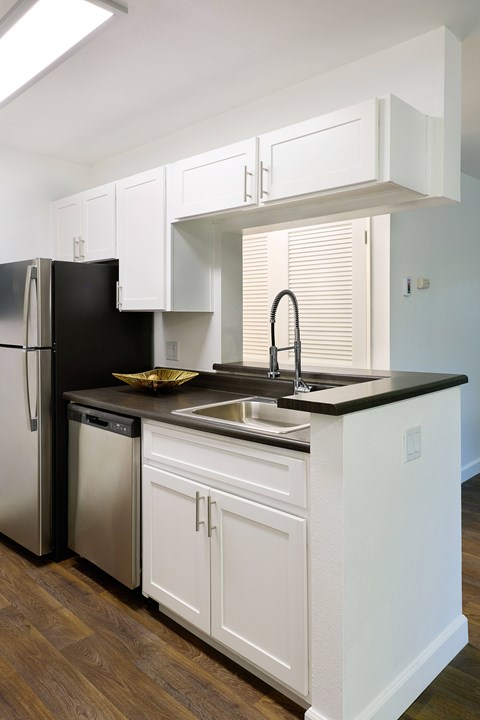 A kitchen with white cabinets and a black fridge.
