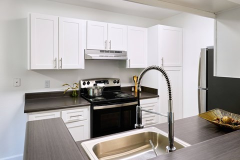 A modern kitchen with white cabinets and a black stove top.