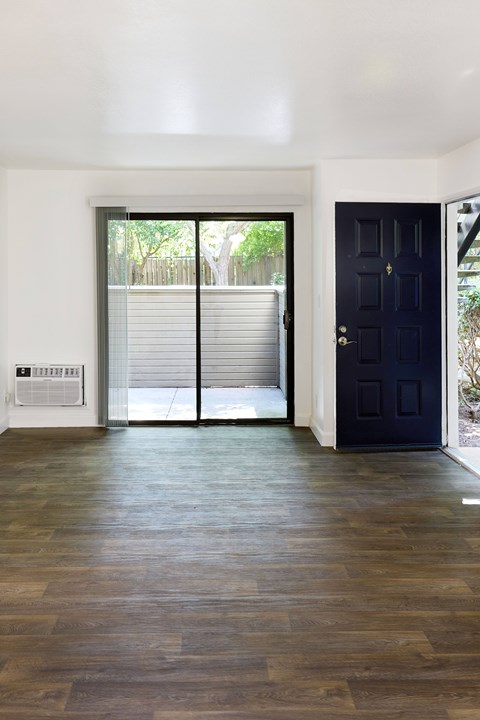 A room with a black door and a sliding glass door leading outside.