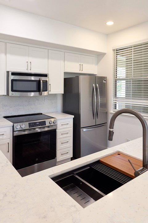 A modern kitchen with a stainless steel refrigerator, microwave, and oven.