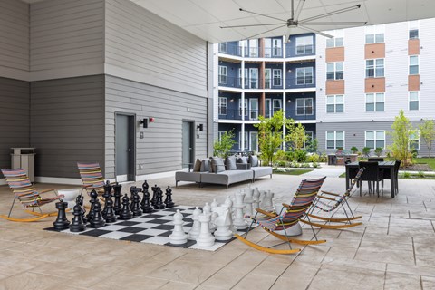 a chess board in the courtyard of an apartment building with chairs and a chess set