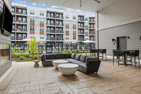 a patio with couches and tables in front of an apartment building
