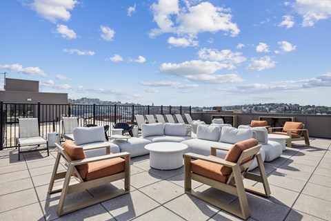 a rooftop lounge area with couches and chairs on a roof