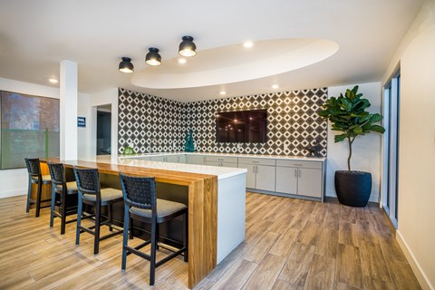 a kitchen with a bar and chairs and a wall with a tv