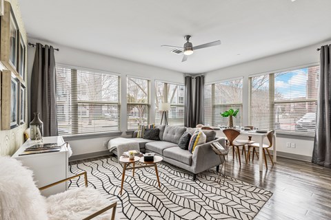 A living room with a grey couch, a coffee table, and a ceiling fan.