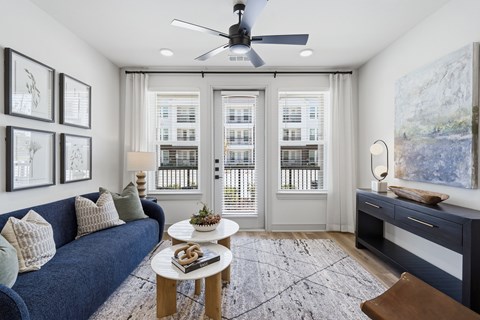 A living room with a blue couch, a coffee table, and a ceiling fan.