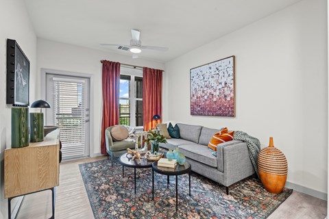 A living room with a grey couch, a coffee table, and a painting on the wall.