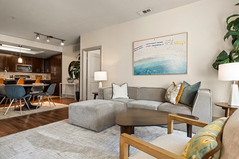 A living room with a grey couch, a coffee table, and a painting on the wall.