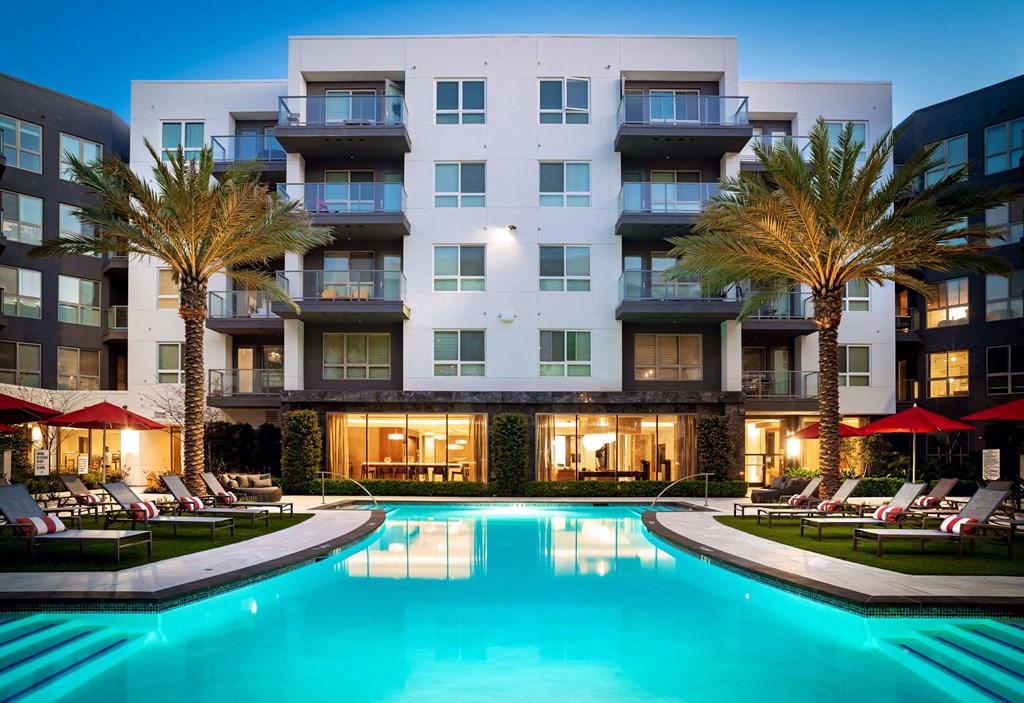 a swimming pool in front of Vora Mission Valley Apartments at night at VORA LUX, San Diego